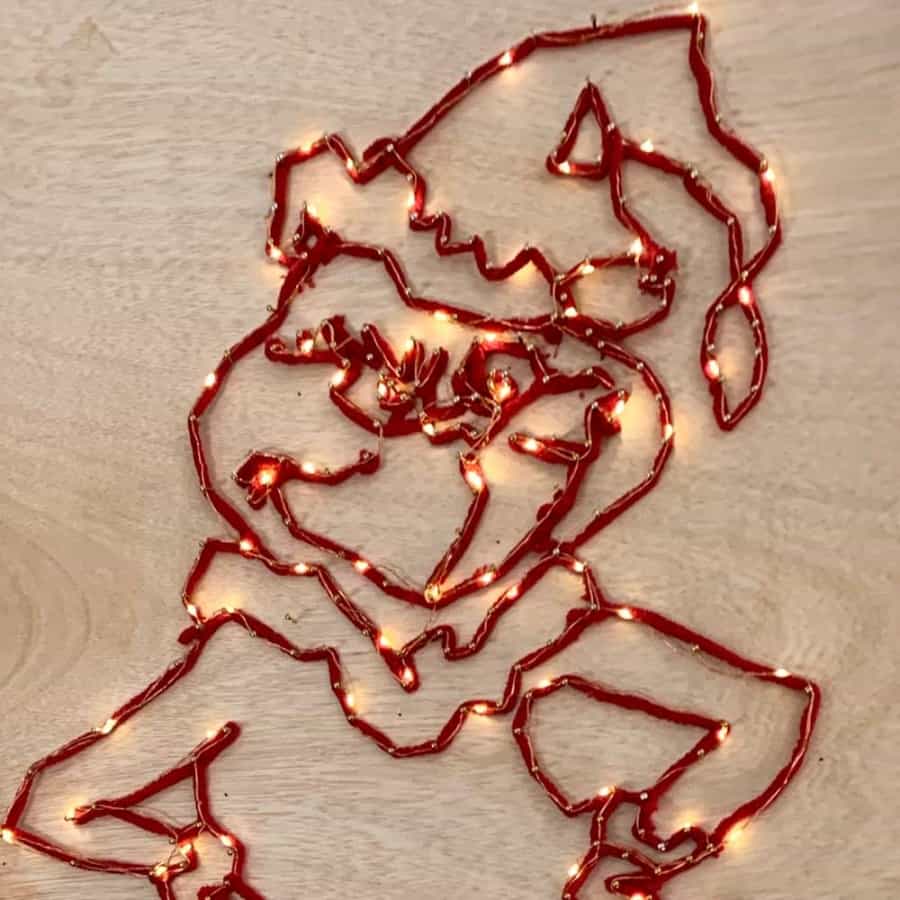 plywood with grinch shape, string and lights