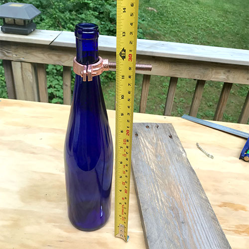 wine bottle with hardware around neck and tape measuring height from bottom