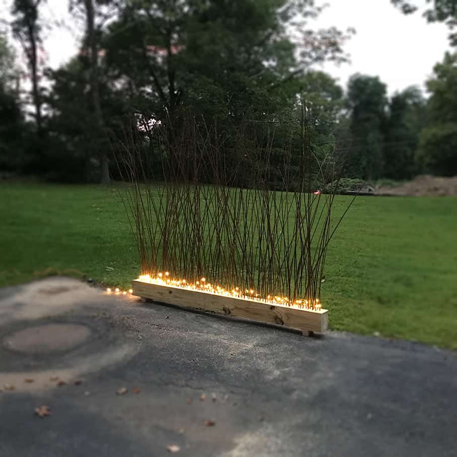 DIY privacy screen with branches in beam, lit with fairy lights