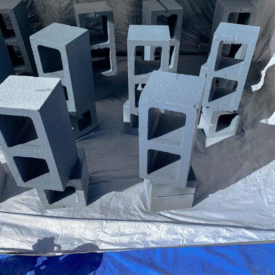 cinder blocks on ends inside sprayer tent with blue paint on them