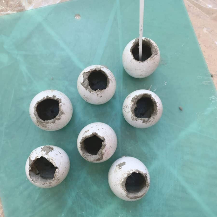 eggshells filled with cement and stir stick sticking out of one of them