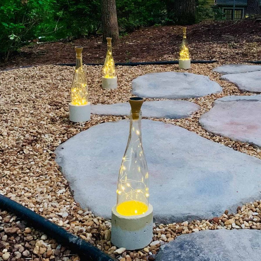 solar fairy lights wine bottle with cement base on stone path