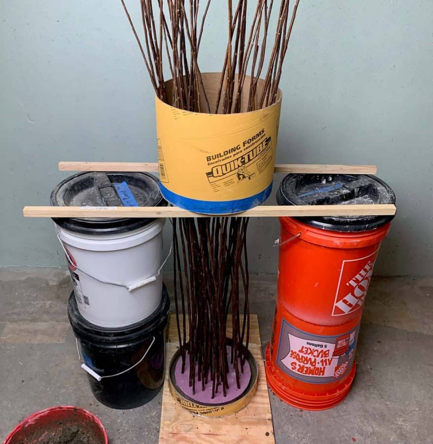 4 buckets supporting the cardboard tube, supporting the diy twig lights stand while inside of cement
