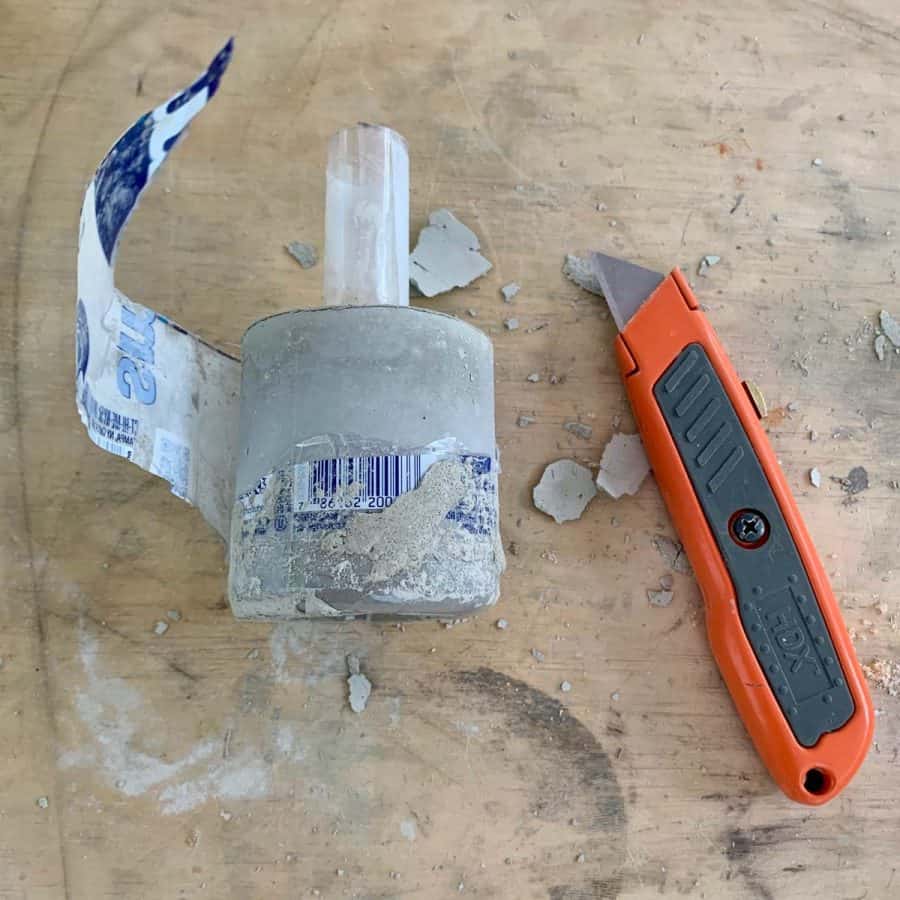 box cutter next to DIY concrete candlestick with bottle plastic partially cut off