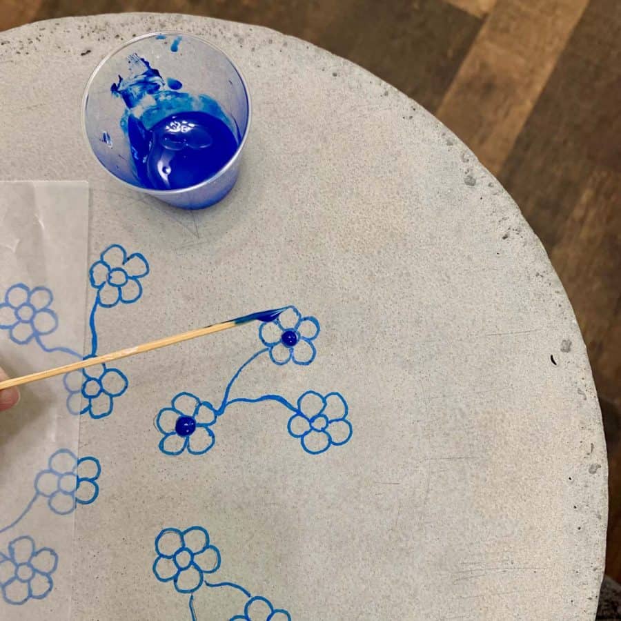 flowers drawn on concrete table top with resin being applied with toothpick