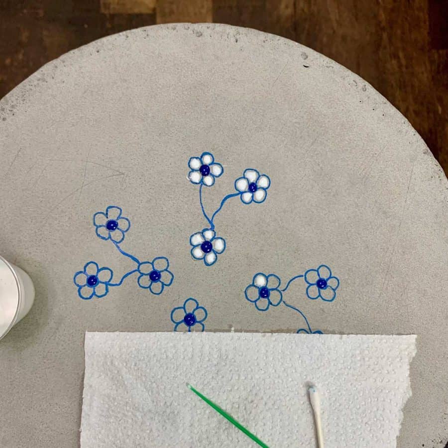 flowers drawn on concrete table top with resin being applied to petals with toothpick