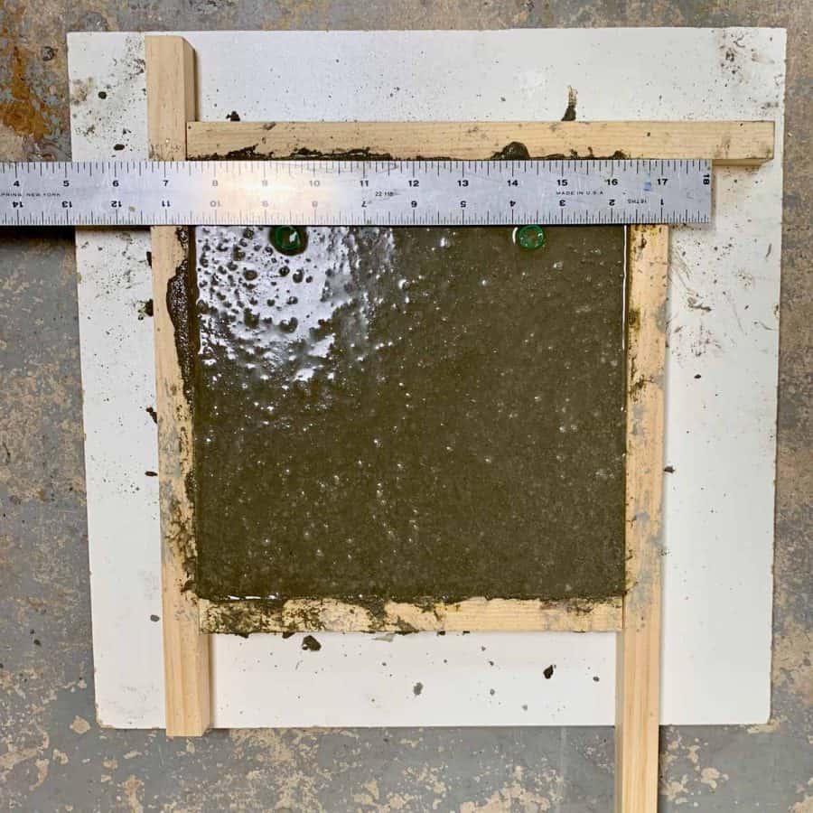 casted concrete in wall tile mold with ruler running across top and straws inserted below