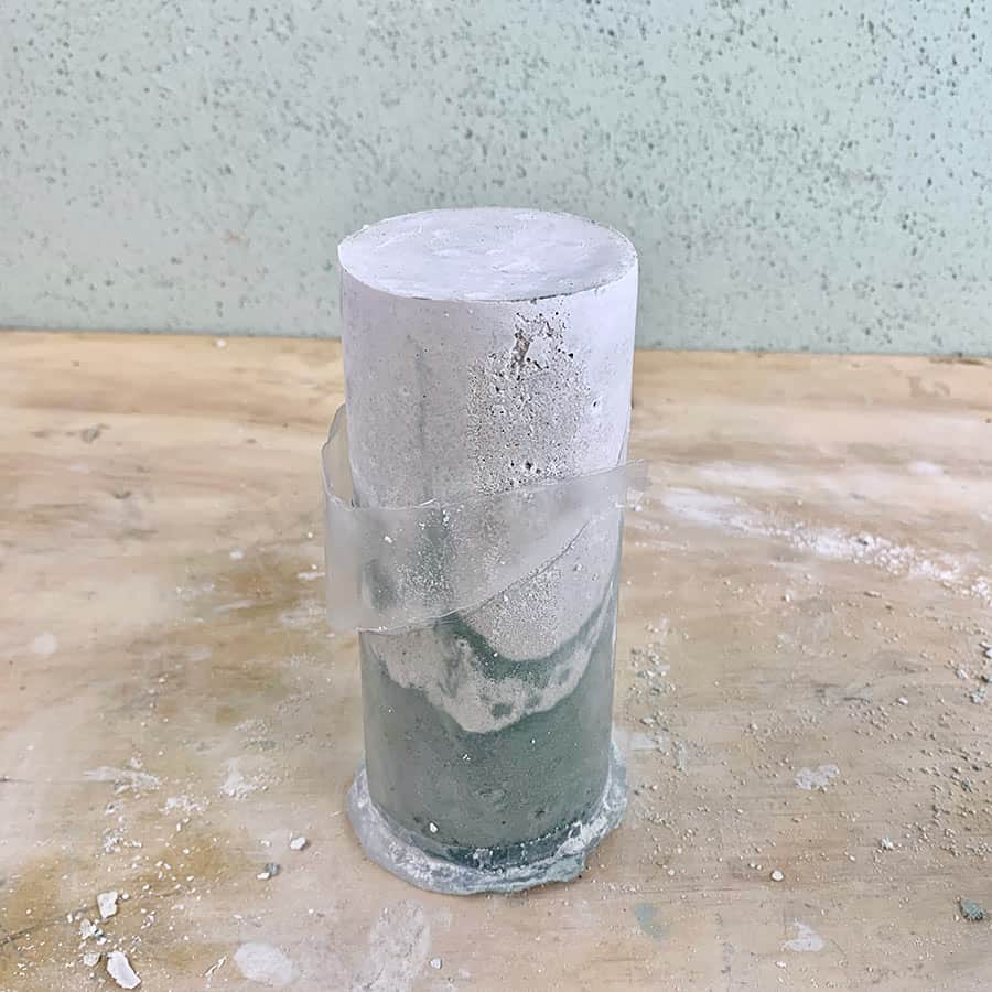 peeling plastic off of cured DIY concrete pillar candle holder