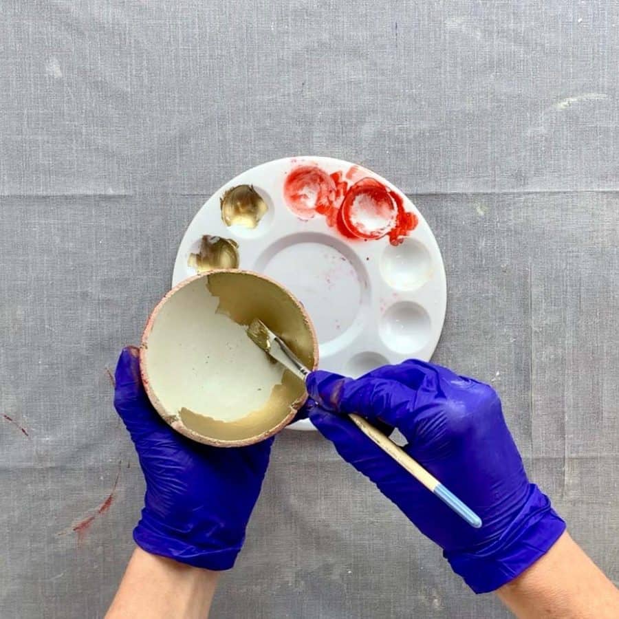 paint brush brushing inside of concrete DIY bowl