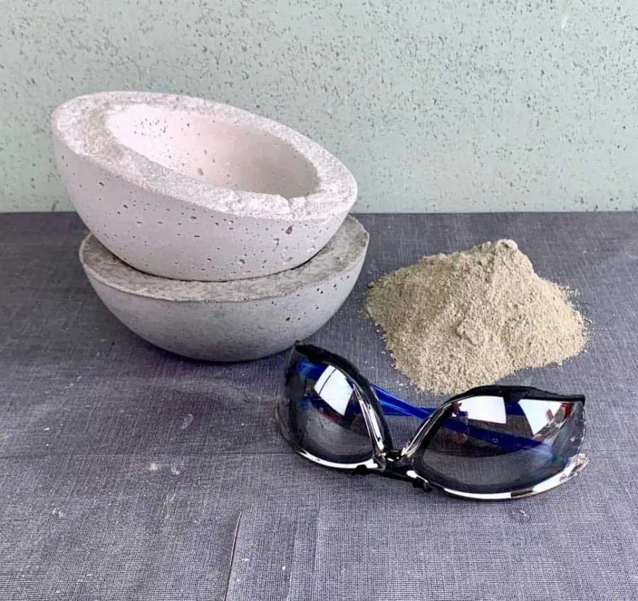 safety glasses, pile of dry cement mix and concrete bowls