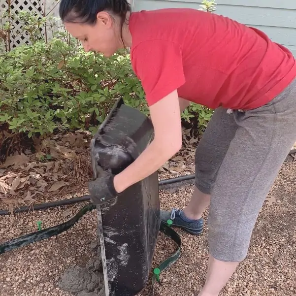 lifting heavy, wet concrete mix and pouring into mold