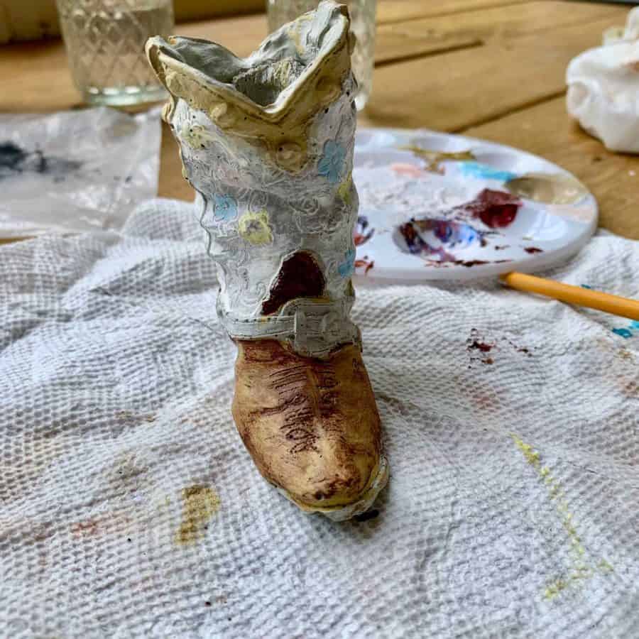 concrete cowboy boot with paint after brownish red rubbed off