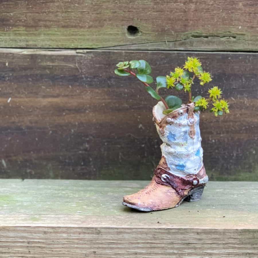 pearly white and tannish/light brown cowboy boot planter with plants inside