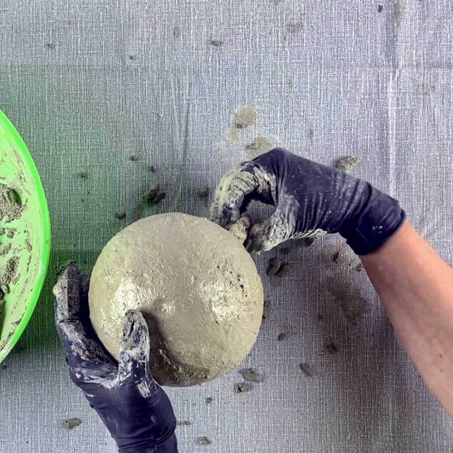 hand pinching cement from bottom of balloon