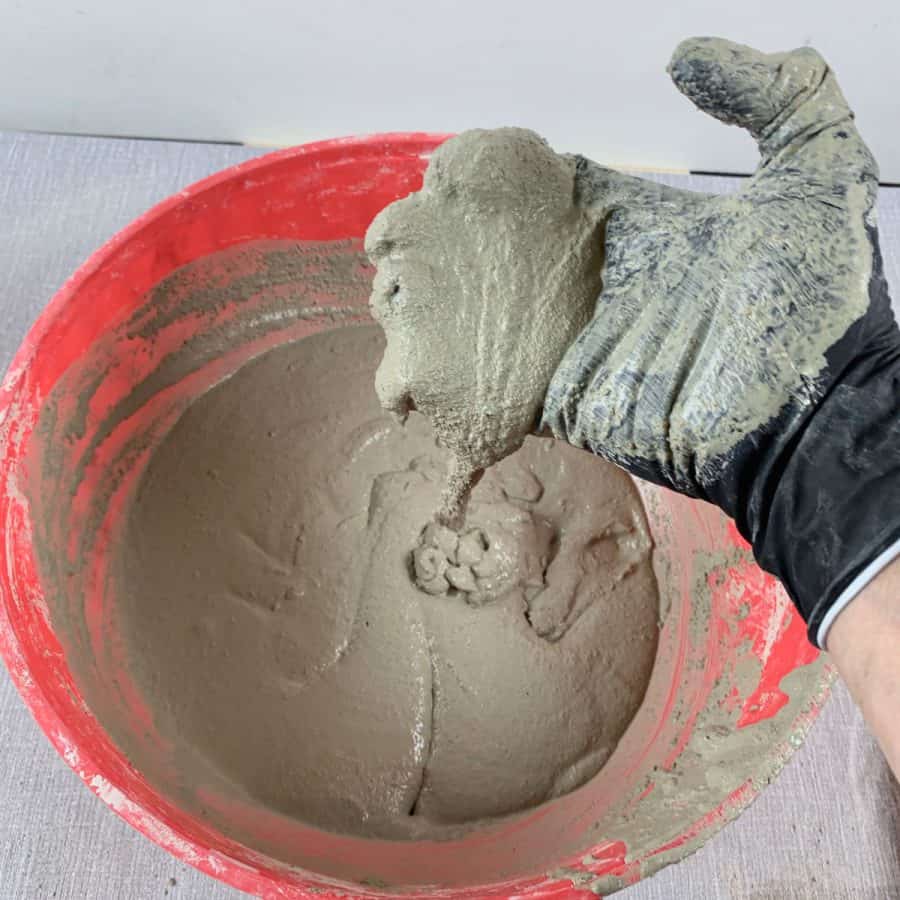 hand with concrete mix slow dripping into bowl