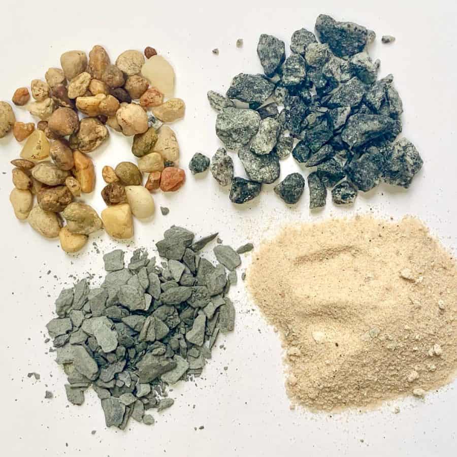 cement vs concrete- four types of concrete aggregates in piles, next to each other - pea gravel, crushed rock, sand and gravel