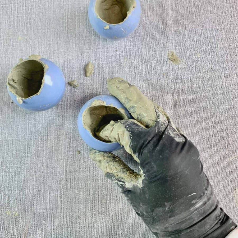 concrete candle- fingers with gloves inside of plastic ball pushing against concrete