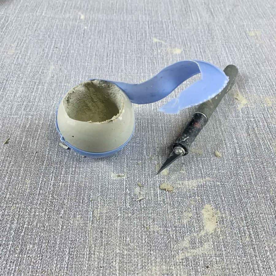 concrete candle- cured concrete candle ball with plastic ripped partially off next to facto knife