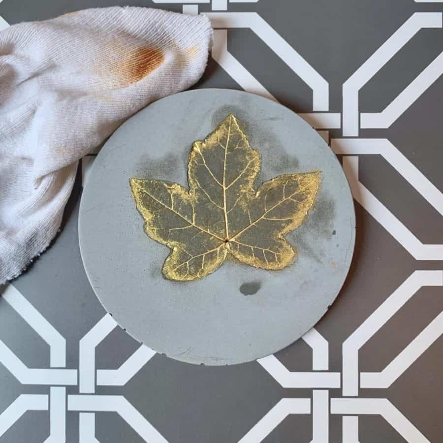 Concrete Coasters-coaster with gold leaf with wet spots and damp cloth next to it.