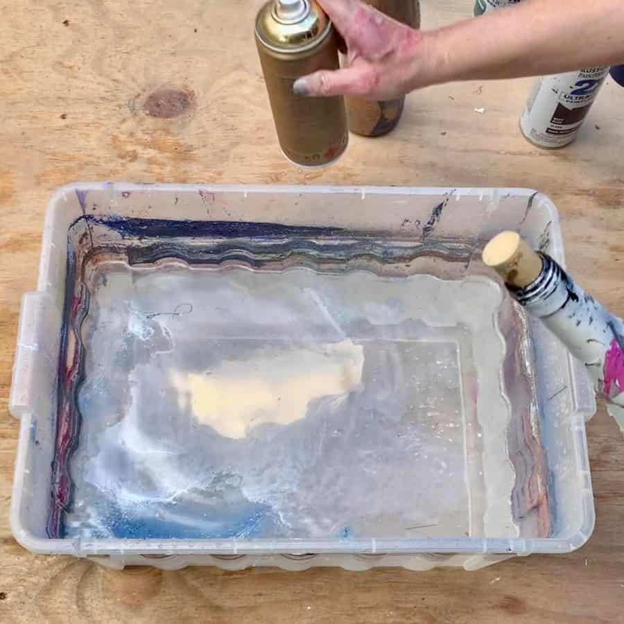 gold spray paint applied to water's surface