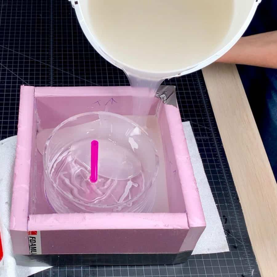 pouring mixed silicone mold mixture into large concrete silicone mold form box