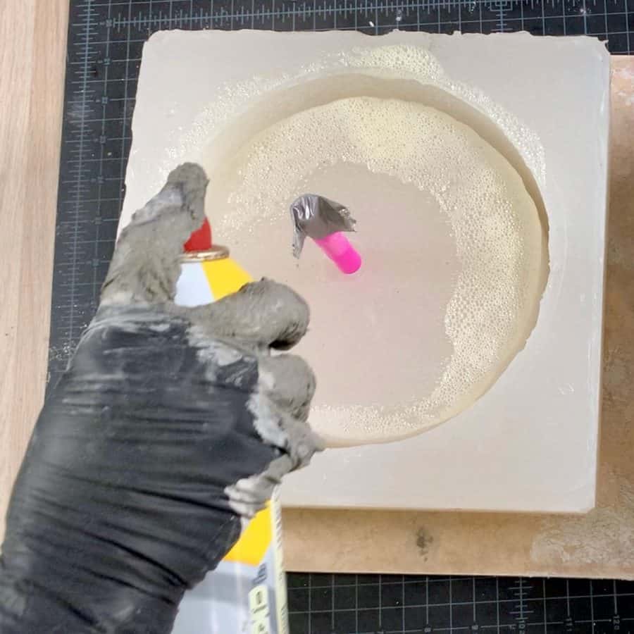 hand spraying cooking oil into silicone mold