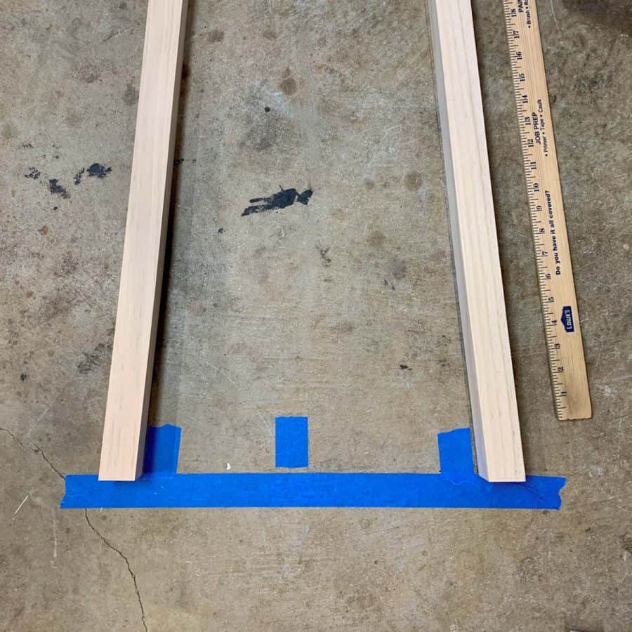 angled 2x2 legs lined up on blue tape line on floor. Bottoms are flat cut at 4.5 degree angle