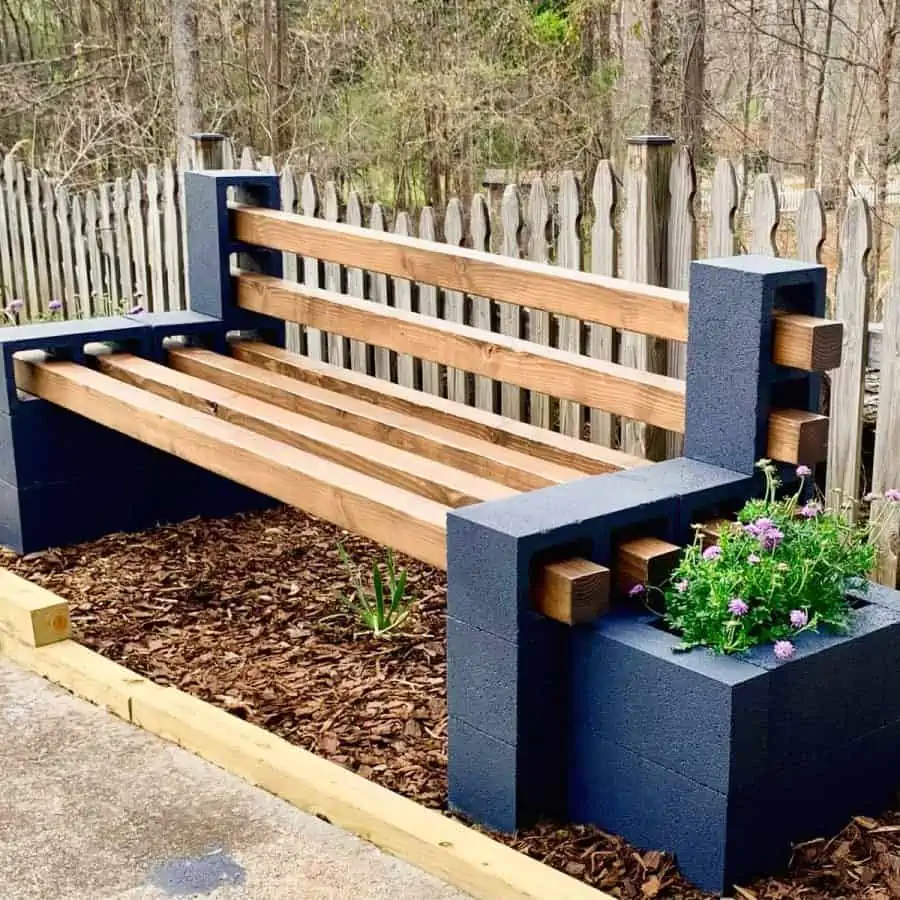 bench made with cinder blocks and timbers flanked by concrete block planter boxes with purple flowers