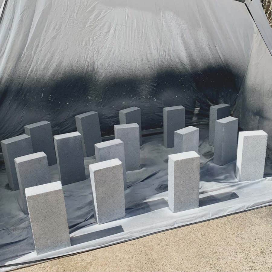concrete blocks lined up on ends inside a paint spray tent painted with white primer