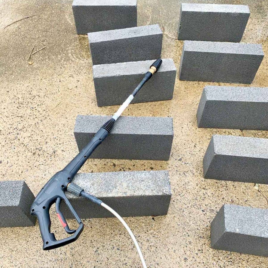 power washer sprayer handle laying on top of wet concrete blocks