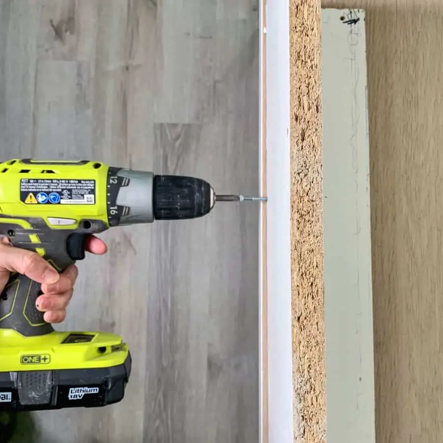 hand holding screw gun screwing base and side boards