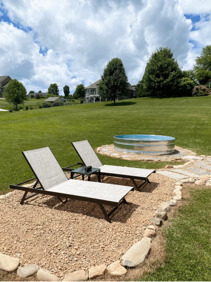 Lawn chairs set up on top of a gravel path that leads to a flagstone path that surrounds a small pool.