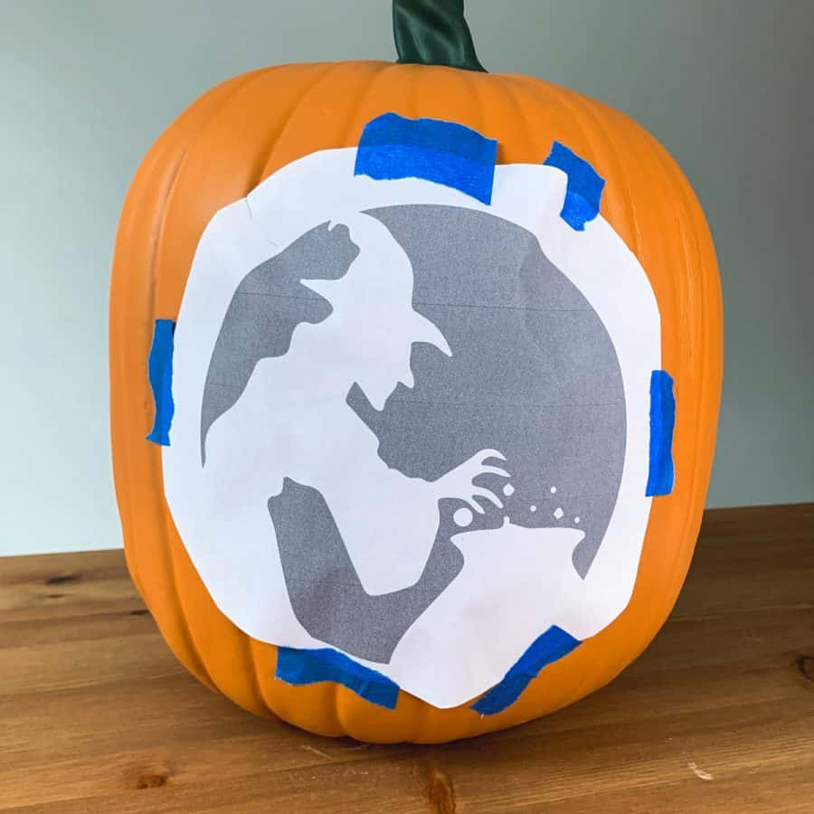 pumpkin with a witch printable taped to it.