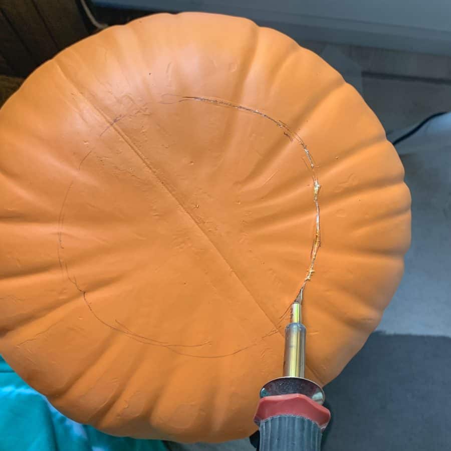 bottom of pumpkin being cut with hot knife