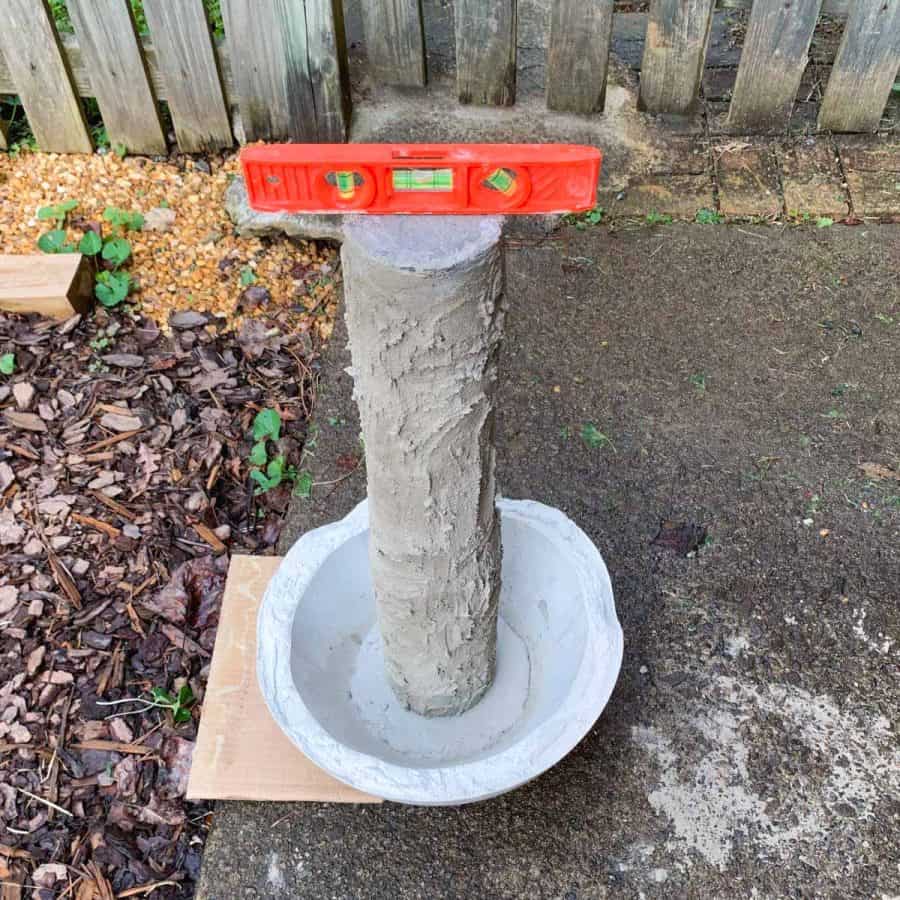 concrete base post inside of cast bowl with a level on top