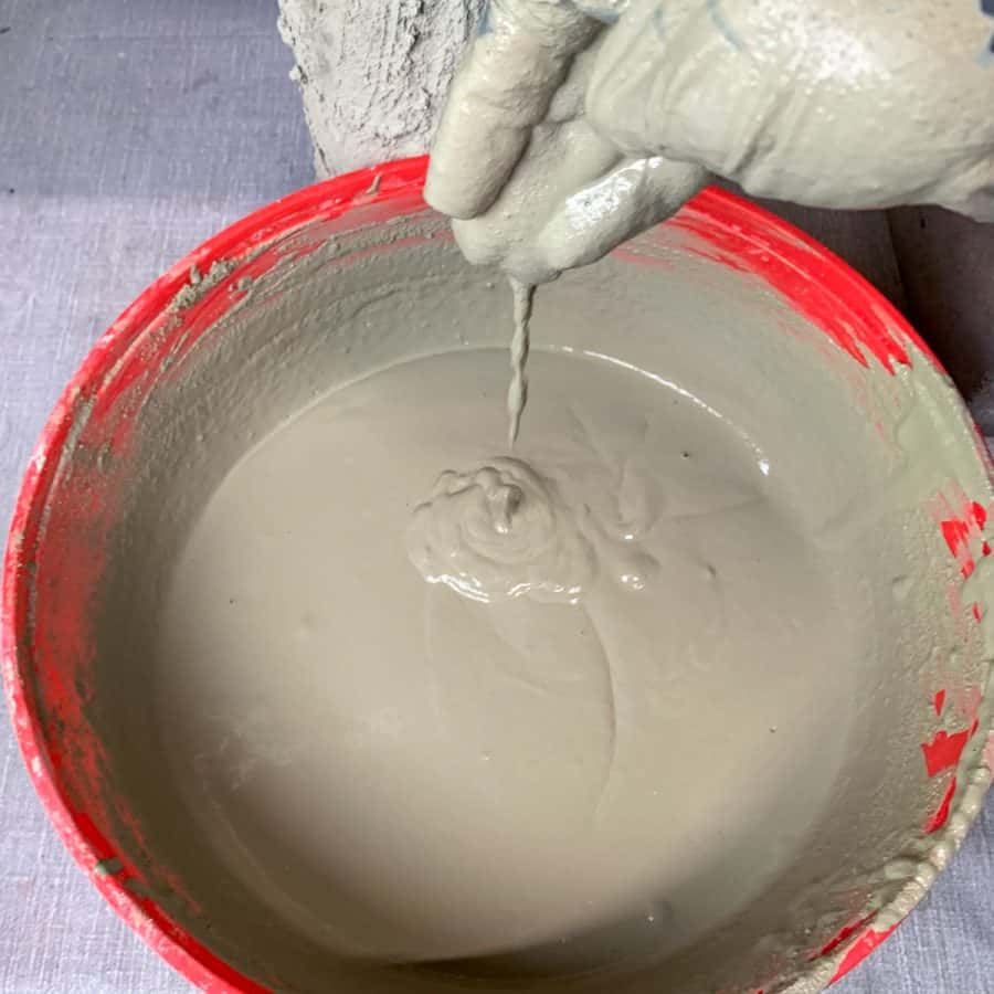 thin mixture of cement dripping from a gloved hand