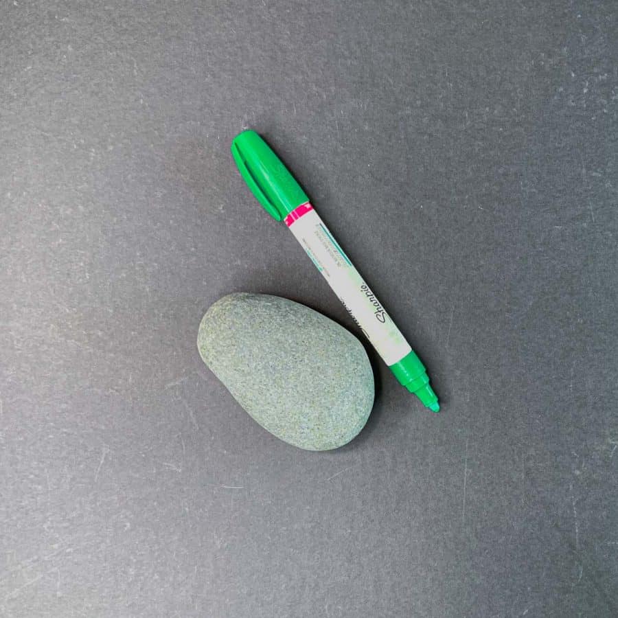 a smooth rock and paint pen in green next to it
