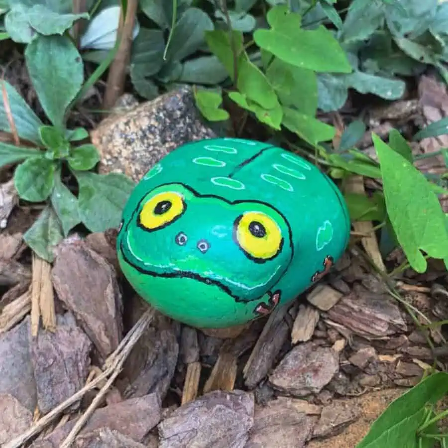 a rock painted like a frog, in a garden