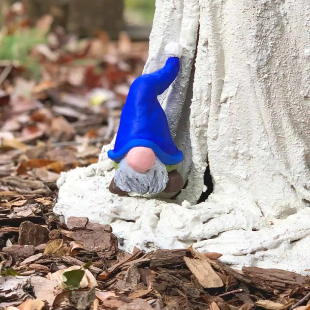 a colorful clay gnome sitting on the stem of a concrete mushroom