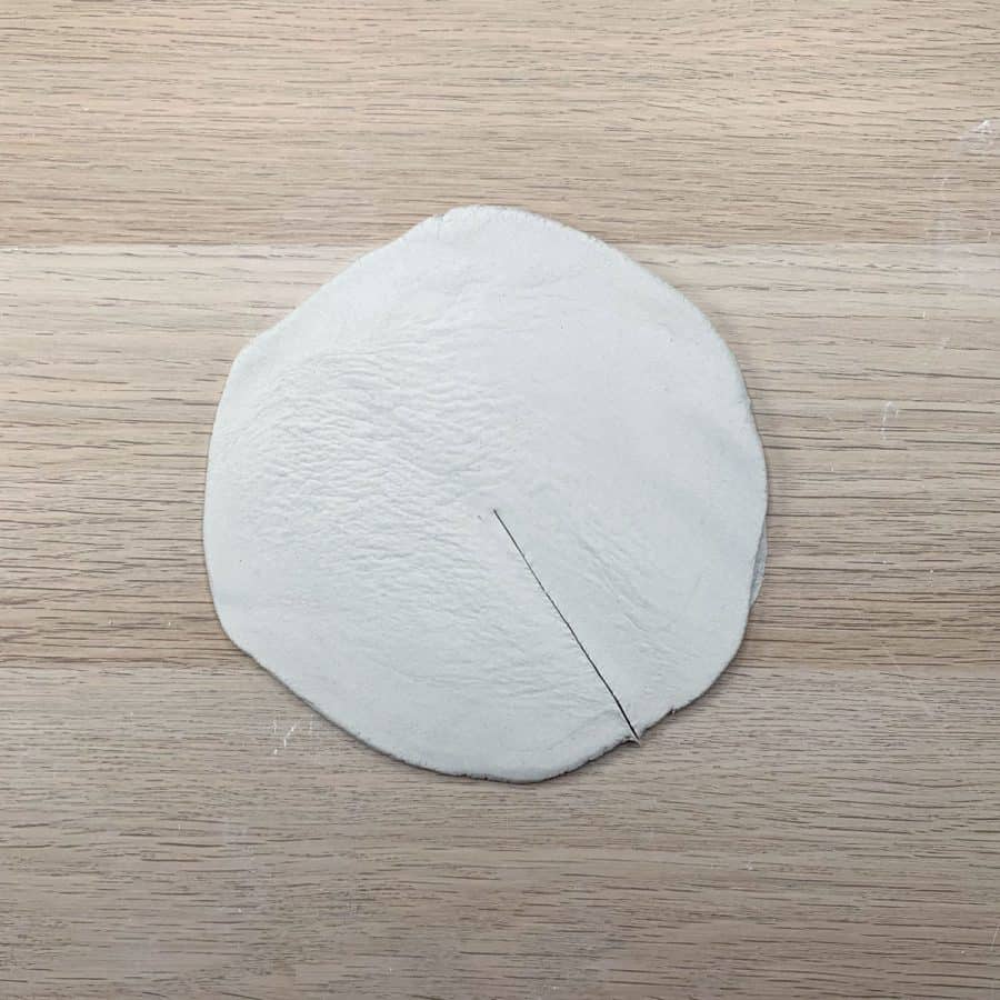 flat, round clay on table with cut halfway down center
