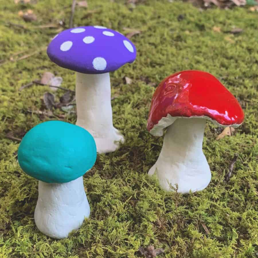 3 small clay mushrooms on top of moss. They are colored bright colors.