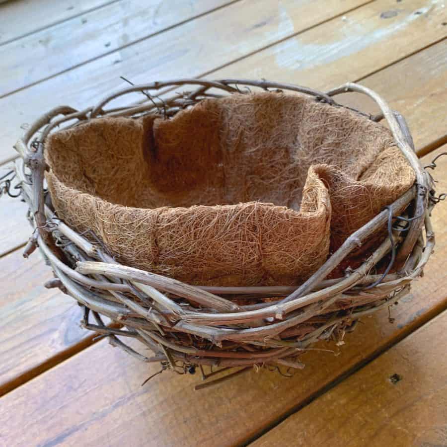 A coconut liner placed inside the basket planter. It is sticking out on one side.