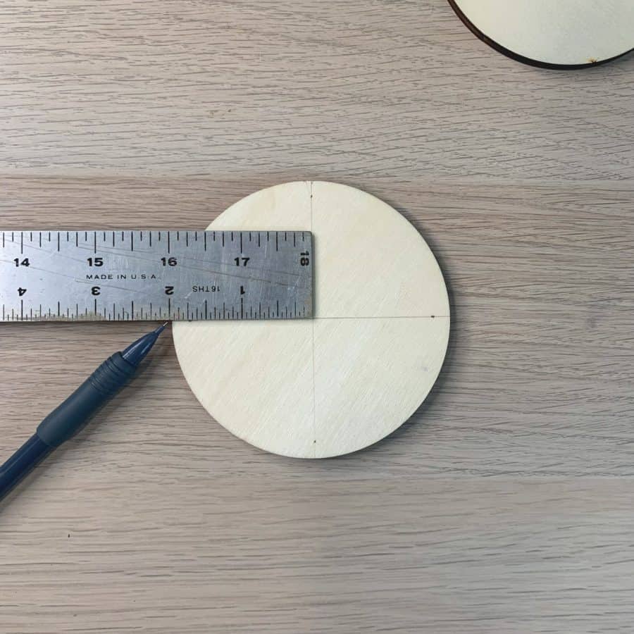ruler on top of wood disc measuring 2 inches in to mark center