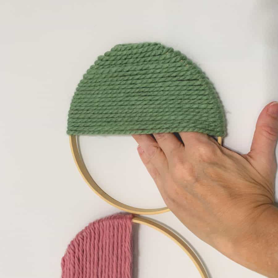 hand pressing the inside of yarn ring where adhesive is attached, against the wall.