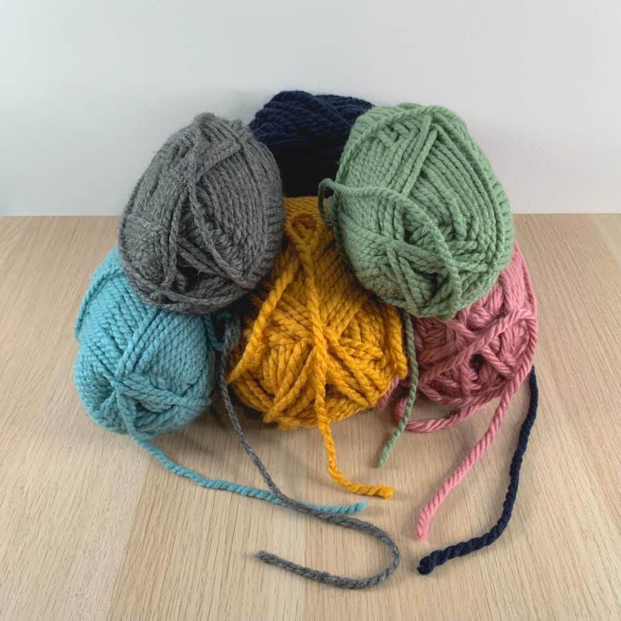 stacked skeins of yarn in mid century modern colors, on a table