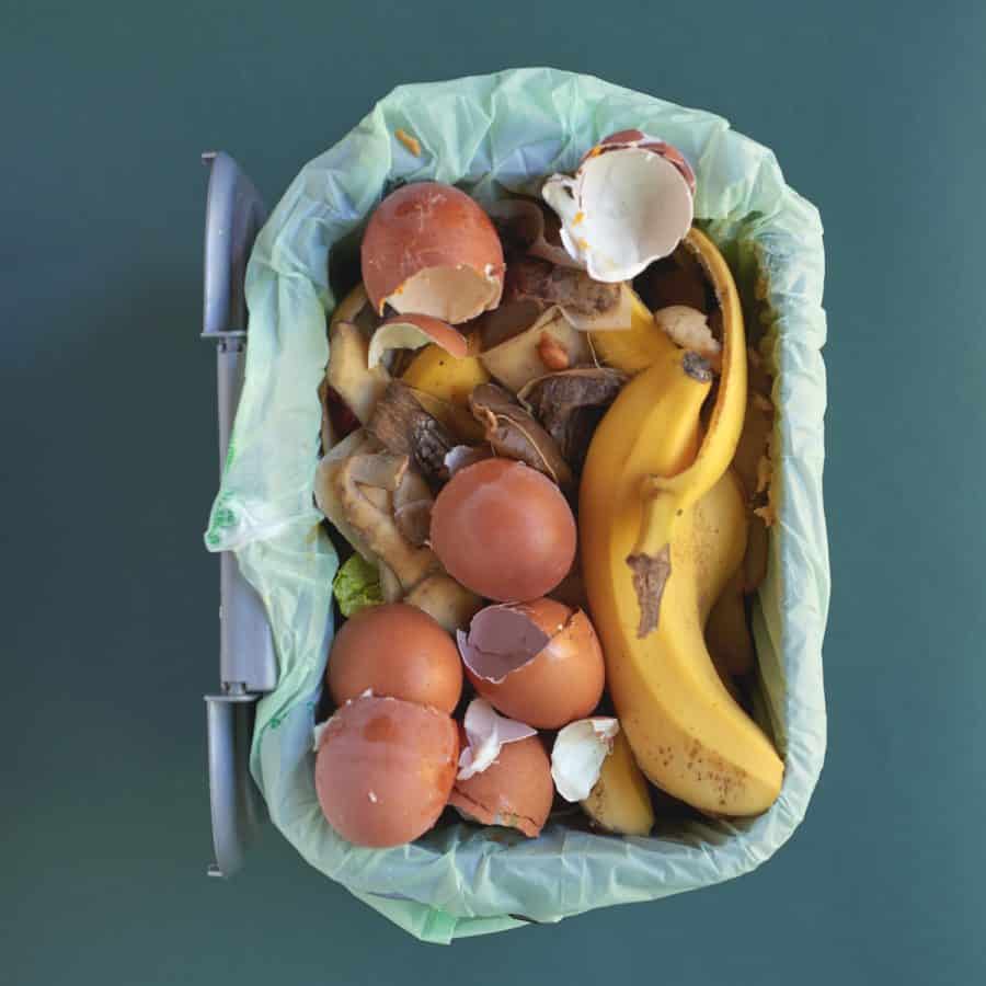A kitchen trash bin filled with food composting waste.