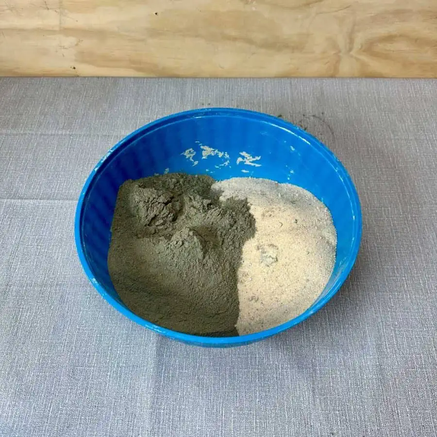 Portland cement on one side of bowl and sand on other side.