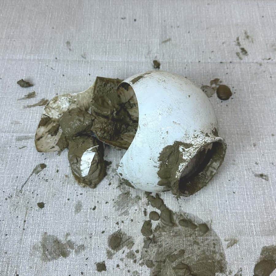 A class globe cracked into pieces with cement pouring out onto table.