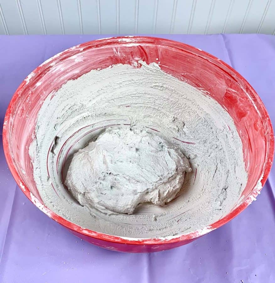A mixing bowl with a lump of wet concrete mix inside.
