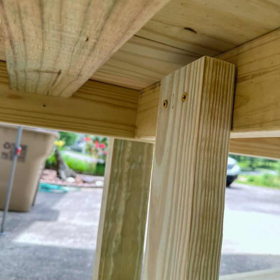 two screws at top of inside half shelf leg pieces, and screwed to center support in potting bench frame.